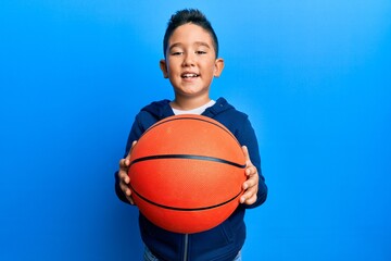 Little boy hispanic kid holding basketball ball smiling with a happy and cool smile on face. showing teeth. © Krakenimages.com