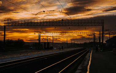 Fototapeta na wymiar Railway station and beautiful colorful sky at sunset. Railway platform in the evening