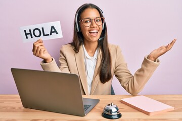 Beautiful hispanic woman wearing operator headset holding hola greenting celebrating achievement with happy smile and winner expression with raised hand © Krakenimages.com