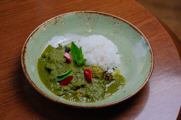 Thai food Vegetable green curry with white rice on old wooden background.