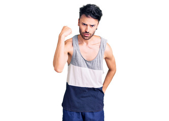 Fototapeta premium Young hispanic man wearing casual clothes angry and mad raising fist frustrated and furious while shouting with anger. rage and aggressive concept.