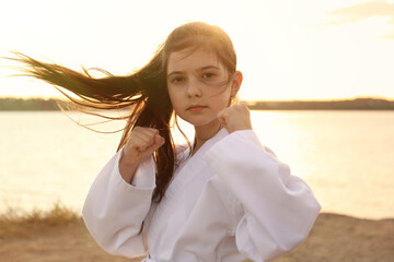 Cute little girl in kimono practicing karate near river at sunset © New Africa