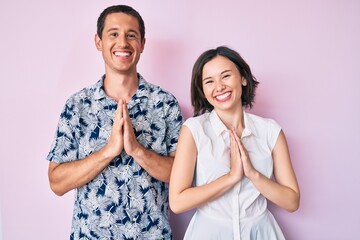 Beautiful couple wearing casual clothes praying with hands together asking for forgiveness smiling confident.