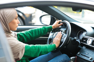 Serious muslim woman driving her car and honking