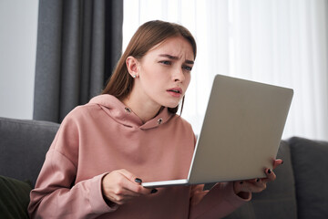 Teenager squinting her eyes while using laptop