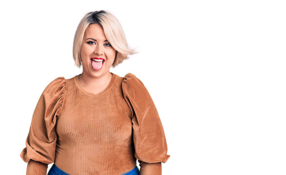 Young blonde plus size woman wearing casual sweater sticking tongue out happy with funny expression. emotion concept.