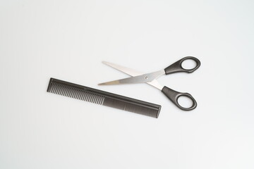 stainless steel scissors with black handle lie and comb on a light table