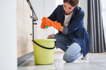 Woman squeezing wet rag in green bucket