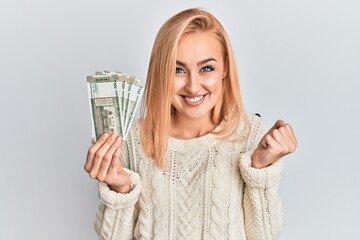 Beautiful caucasian woman holding 500 indian rupee banknotes screaming proud, celebrating victory and success very excited with raised arm