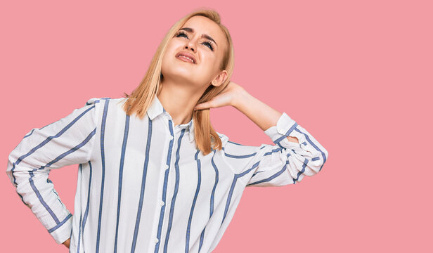 Beautiful caucasian woman wearing casual clothes suffering of neck ache injury, touching neck with hand, muscular pain