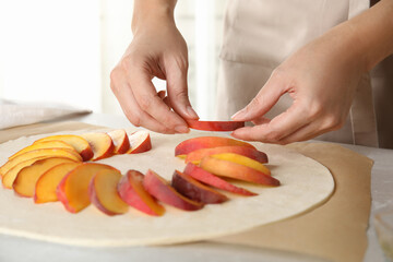 Obraz na płótnie Canvas Woman making peach pie at kitchen table, closeup