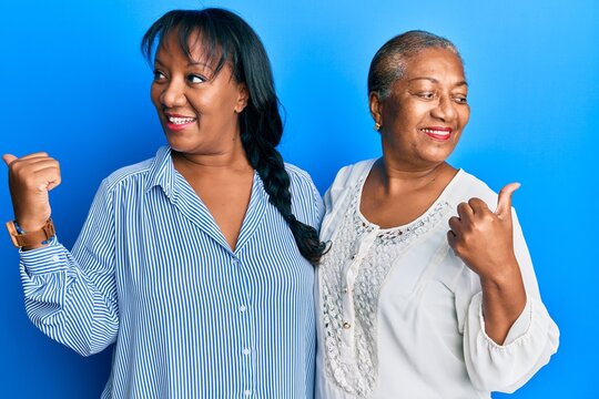 Hispanic Family Of Mother And Daughter Hugging Together With Love Pointing Thumb Up To The Side Smiling Happy With Open Mouth