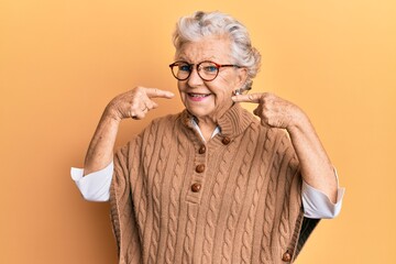 Senior grey-haired woman wearing casual clothes and glasses smiling cheerful showing and pointing with fingers teeth and mouth. dental health concept.