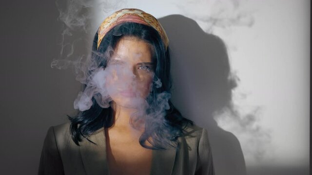 girl smokes a cigarette and casts a shadow on the wall