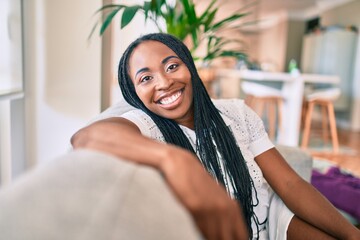 Young african american woman smiling happy sitting on the sofa at home