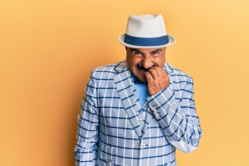 Mature middle east man with mustache wearing vintage and elegant fashion style looking stressed and nervous with hands on mouth biting nails. anxiety problem.