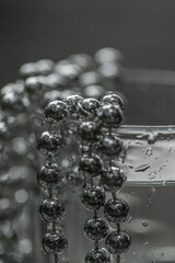 Pearl beads in a glass with water drops in silver color