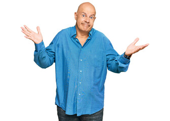 Middle age bald man wearing casual clothes clueless and confused expression with arms and hands...