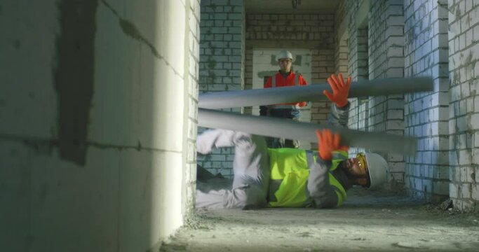 Builder falling under pipes in front of colleague