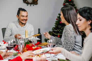 Mexico Christmas dinner: group of mexican friends eating together and drinking wine