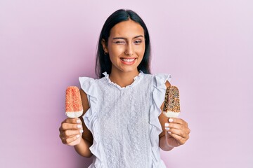 Young brunette arab woman holding ice cream winking looking at the camera with sexy expression,...