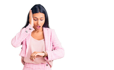 Young beautiful latin girl wearing business clothes looking at the watch time worried, afraid of...