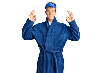 Young handsome man wearing sleep mask and bathrobe relax and smiling with eyes closed doing meditation gesture with fingers. yoga concept.