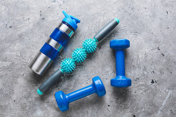 Body roller with dumbbells and bottle of water on grunge background