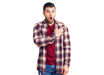 Fototapeta premium Young handsome man wearing casual shirt surprised pointing with finger to the side, open mouth amazed expression.