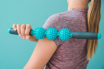 Sportswoman massaging herself with body roller on color background