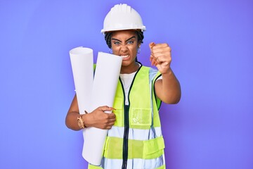 Young african american woman with braids wearing safety helmet holding blueprints annoyed and frustrated shouting with anger, yelling crazy with anger and hand raised
