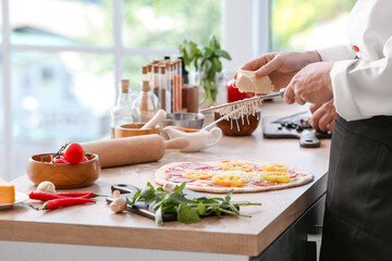 Chef making tasty pizza in kitchen