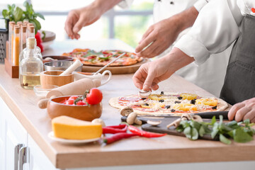 Obraz na płótnie Canvas Chefs cooking tasty pizza in kitchen