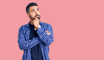 Fototapeta premium Young hispanic man wearing casual clothes with hand on chin thinking about question, pensive expression. smiling with thoughtful face. doubt concept.