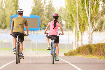 Sporty young couple riding bicycles outdoors