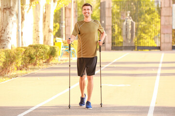 Young man training with walking poles outdoors