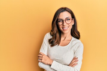 Young brunette woman wearing casual clothes and glasses happy face smiling with crossed arms looking at the camera. positive person.