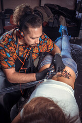 Master of the art of tattooing making a tattoo in tattoo parlour