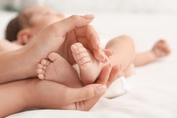 Obraz na płótnie Canvas Mother's hands holding tiny legs of her baby, closeup