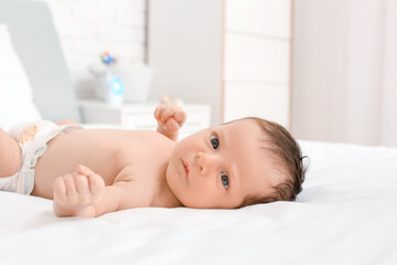 Cute little baby lying on bed at home