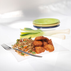 Tasty portion of Chinese rice with pieces of breaded chicken; photo on white background.