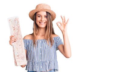 Obraz na płótnie Canvas Young beautiful girl wearing hat holding city map doing ok sign with fingers, smiling friendly gesturing excellent symbol