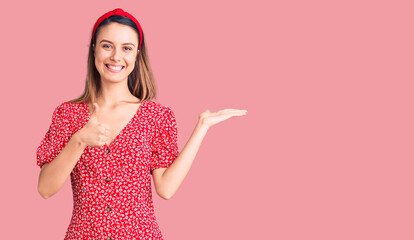 Young beautiful girl wearing dress and diadem showing palm hand and doing ok gesture with thumbs up, smiling happy and cheerful