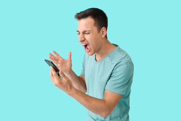 Stressed young man with mobile phone on color background