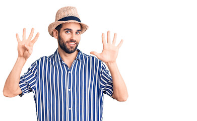 Young handsome man with beard wearing summer hat and striped shirt showing and pointing up with...