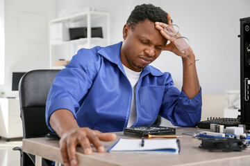 African-American technician repairing computer in service center