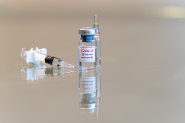 A closeup vial of COVID-19 Coronvavirus live virus biohazard culture with a syringe and needle tip in the front - 067