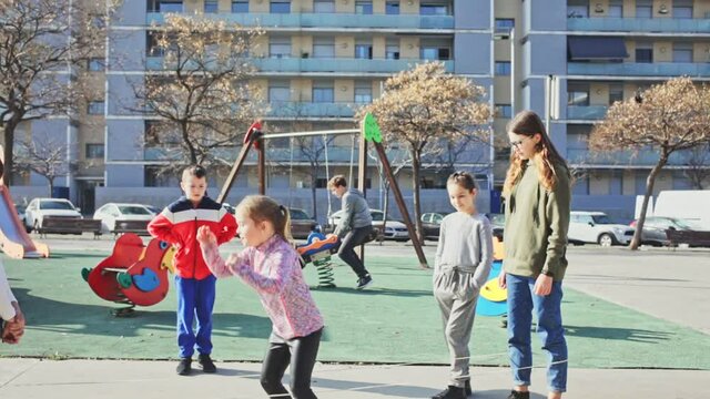 Happy kids playing together with elastic jumping rope outdoors at urban landscape