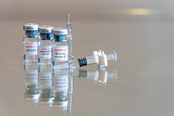 A closeup triple vial set of COVID-19 Coronvavirus live virus biohazard culture with a syringe on the right and needle tip in the front - 124