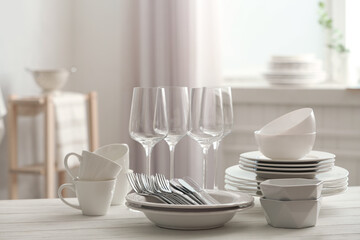 Fototapeta na wymiar Set of clean dishware, cutlery and wineglasses on white table indoors